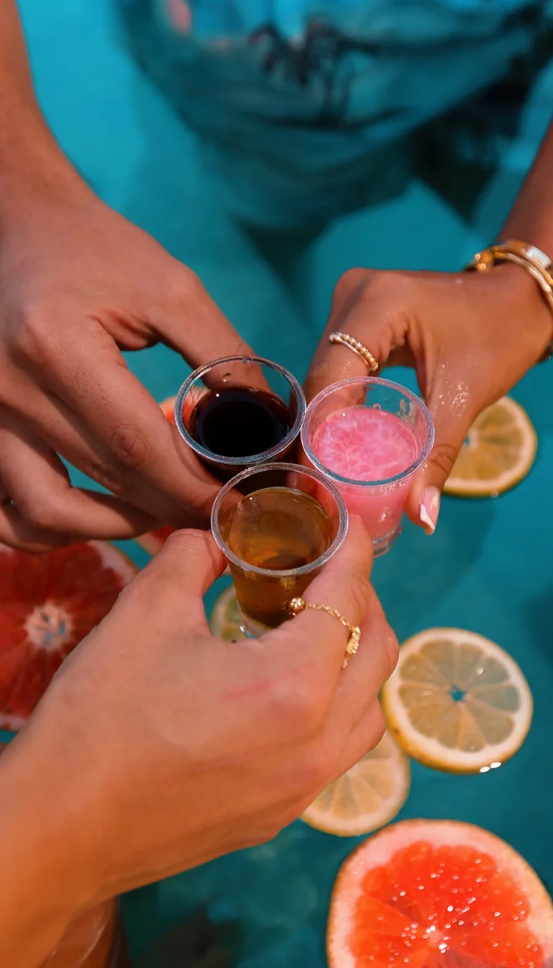 Friends bringing HotShot shots together for a poolside cheers